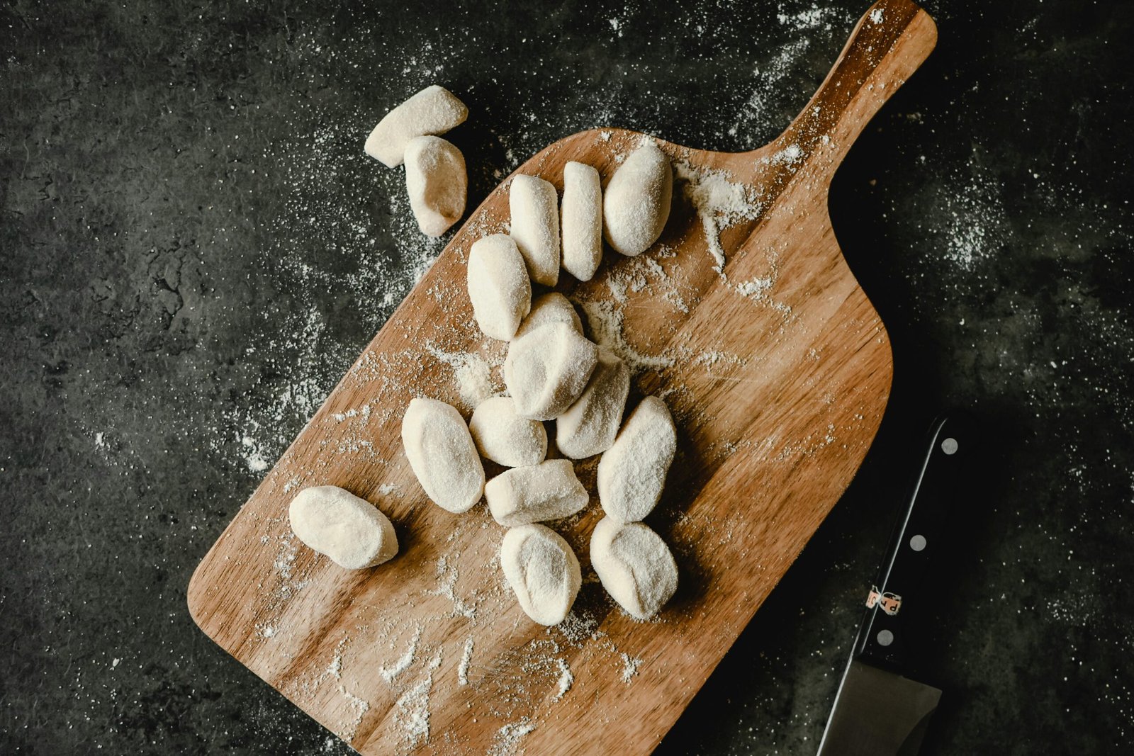 Oval Shaped Dough with Flour on Brown Wooden Chopping Board